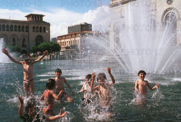 A hot day in yerevan, children cool off in the fountain in the central square, armenia, 1996.