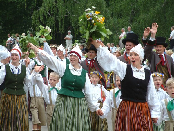 Participants in a traditional folk song and dance festival marching through the center of riga, latvia, 2003  .