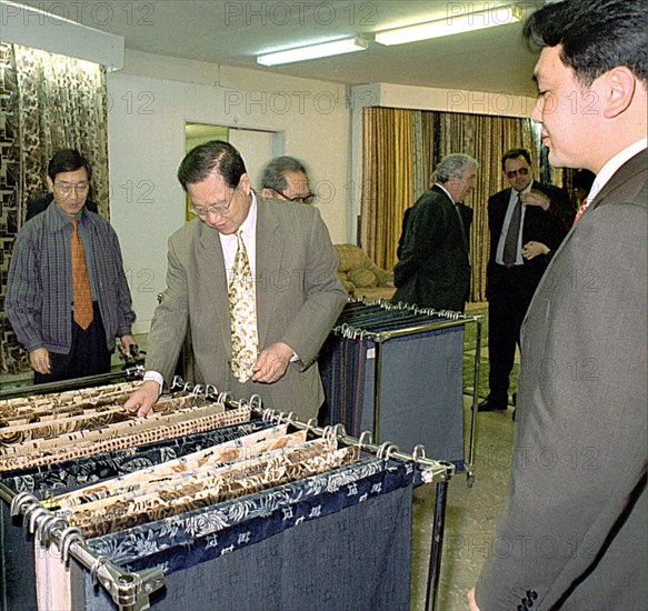 Orenburg, russia, june 16 2003: head of the chinese delegation from shantung province chao chihao, centre, seen inspecting the assortment of the materials, produced by 'orenteks' enterprise during his visit to orenburg (south ural), the chinese are interested in the exchange of ural natural and food resources, medical service into qualitative chinese goods of a broad usage, (photo by valery bushukhin / itar-tass).