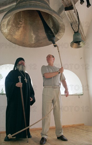 Russia, august 21 2001, president vladimir putin (right) ringing the bell during his visit to the spaso-preobrazhensky (savior's transfiguration) monastery at the vallam island, accompanied by archimandrite pankratiy, (left) the monastery's hegumen.
