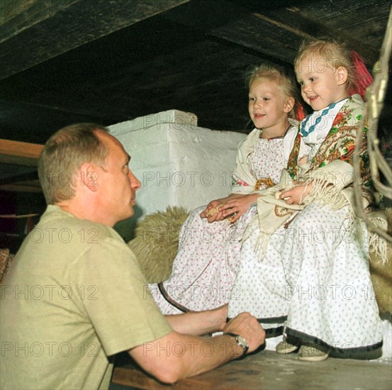 Petrozavodsk, karelia, russia, august 19 2001, president vladimir putin who spends part of his vacation in karelia pictured talking with natasha and vasilisa popovs ,participants of the 'kizhi' folklore ensemble, while visiting on saturday a traditional karelian home, these houses have a specific layout which combines the living quarters and household premises under one roof,    19,08,2001.