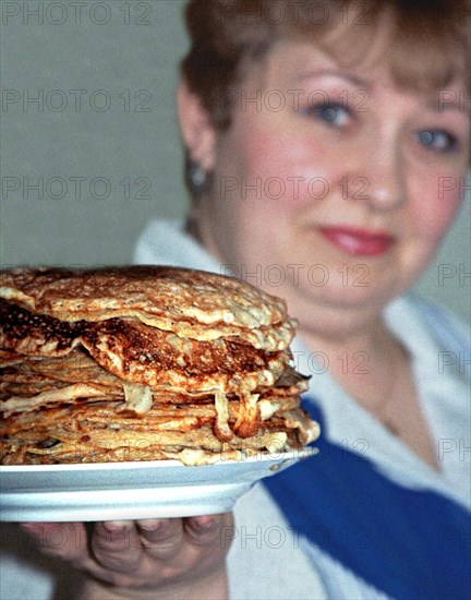 Yekaterinburg, russia, 3/13/02: yekaterina zasada, a resident of yekaterinburg, showing off a pile of bliny (pancakes) she has cooked for maslenitsa (shrovetide), which is celebrated this week, traditionally the delicious bliny are made of combined wheat and buckwheat flour and can be served with sour cream, honey, jam or red caviar.