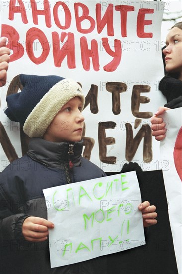 Moscow, russia, october 25 2002: a little boy whose father is being held hostage by terrorists at the palace of culture of the ball-bearing plant pictured participating in mass meeting of relatives of hostages, the unofficial meeting with slogans to stop the war in chechnya was organized by relatives of the hostages under the pressure of terrorists near st, basil's cathedral on friday.