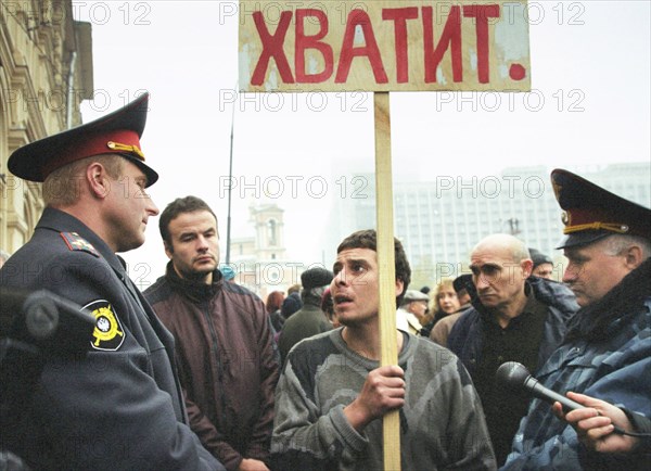 Moscow,russia, october 25 2002: policemen trying to pursuade a demonstrator with a slogan 'enough' in hand to stop his unauthorized protest action during the meeting which was organized by relatives of the hostages under the pressure of the terrorists , on friday.