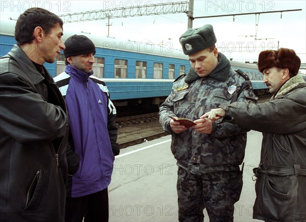 Belarus, november 12 2002: a policeman examines documents of chechen men who wish to leave for poland, at the brest railway terminal, more than 300 natives of chechnya, who are russian citizens, have amassed near the brest customs post, seeking to leave, polish border guards stopped the admission of ethnic chechens on october 26 in light of the hostage crisis in moscow.