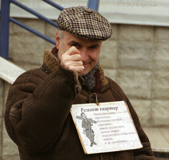 Moscow, russia, november 25 2002: ukrainian gastarbeiter (guest worker) with an attached poster enumerating kinds of flat repair work keeps his post in one of illegal labour markets that still exist in moscow despite the measures taken to reduce the number of illegal migrants, according to the federal immigration service the rate of labour migration varies between 3, 5and 5 million people, the official figure being as little as 320-340,000, (photo yulia artyukova) .