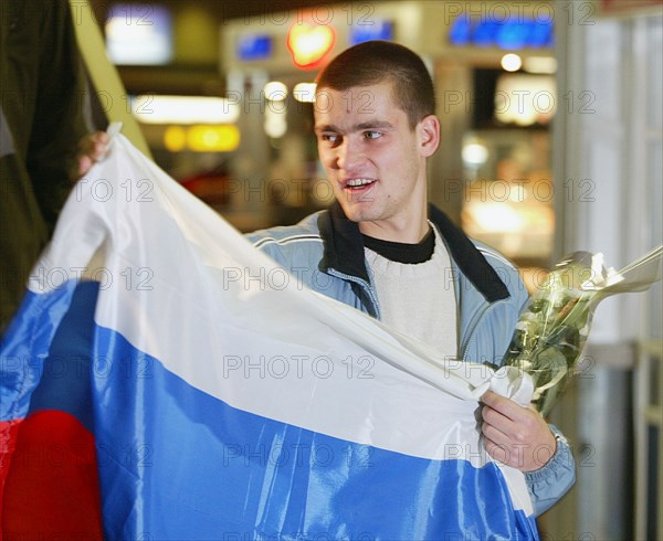 Moscow, russia, december 3 2002: russian tennis player mikhail youzhny, who scored the decisive point and brought the win of the davis cup to the russian team , pictured with a russian flag at the sheremetyevo airport, as he returned to moscow on monday evening, (photo itar-tass/vitaly belousov).