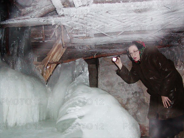 Nizhni novgorod, russia, january 14 2003: valentina kotyashova pictured examining the basement of her house after heavy frosts that paralyzed the water and heat supply pipes, people in 176 old houses in the centre of the city remained without heat and water supply in nizhni novgorod due to severe frosts, (photo itar-tass/ roman yarovitsyn) .