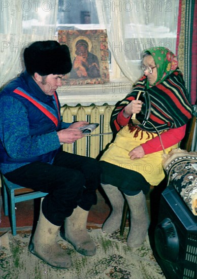 Petrozavodsk, russia, january, 16 2003: 86-year-old yevdokiya obukhovskaya (right) and her son-in-law ivan pukroyev trying to get some warmth from an iron, central steam heating and gas supply have not been restored in many apartments of petrozavodsk after recent disastrous frosts, , (photo itar-tass/semyon maisterman) .