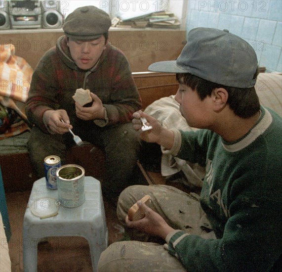 Chinese guest workers during a lunch break, in vladivostok, russia, january 28 2003, russian businessmen like to hire foreign citizens (chinese, vietnamese, north koreans) who agree to work under any unfavourable conditions, the administration of russia's maritime territory decided to hire over 500 guest workers in the current year, basically to be employed for low paying manual jobs.