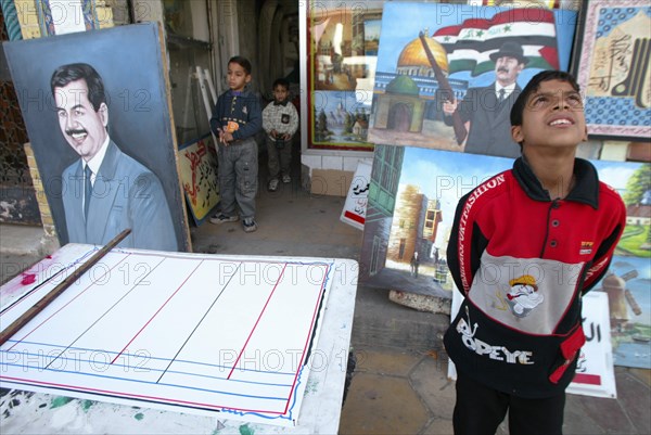 Baghdad, iraq, february 17 2003: a young resident of bagdad pictured viewing some works of a street artist in downtown the city.