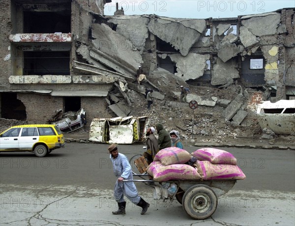 Kabul, afghanistan 2/03, a man hauls a cart loaded with food through the ruined streets of the capital.