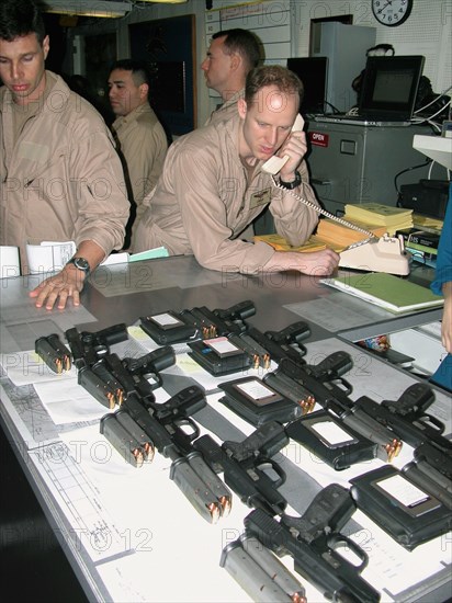 Mediterranean sea, uss theodore roosevelt, march 22, 2003, servicemen pictured prior to the briefing for pilots, held here aboard the aircraft carrier theodore roosevelt before the beginning of the military operation against iraq, pilots have beretta pistols (foreground) with them both in training and combat missions.