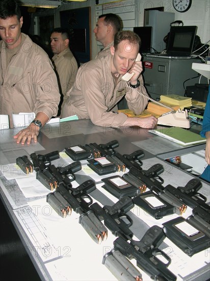 Mediterranean sea, uss theodore roosevelt, march 22, 2003, servicemen pictured prior to the briefing for pilots, held here aboard the aircraft carrier theodore roosevelt before the beginning of the military operation against iraq, pilots have beretta pistols (foreground) with them both in training and combat missions.