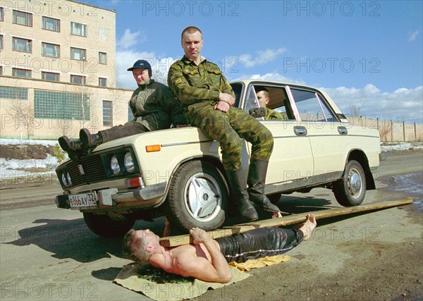 Physical endurance: firefighters, bryansk, russia, march 27 2003, captain of the russian interior ministry forces, guard commander of a bryansk fighfighters' unit mikhail karpeshin (bottom) demonstrates his unique physical abilities, lying on broken glass and holding a car with three men on his chest, karpeshin formerly worked as circus performer, (photo itar-tass/vladimir gorovykh)  .