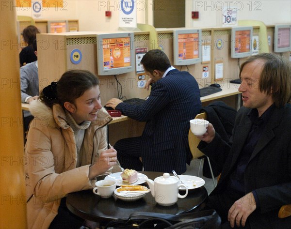 A man and woman having tea and cake at the cafemax internet centre in pyatnitskaya, moscow, russia.