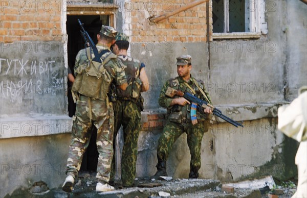 Members of the russian rapid action police (sobr) doing a house to house search during a three hour battle with chechen militants in grozny, chechnya, may 2000, writing on the wall reads: 'people live here'.
