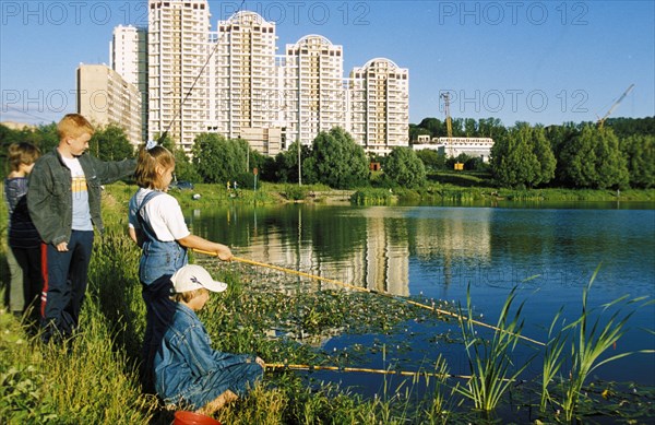 Kids fishing in a city pond in a residential district of moscow, aug, 2000.