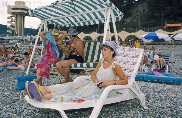 Vacationers enjoying the 'velvet season' (fall) on a pebble beach in sochi, the famous resort city on the black sea coast, krasnodar region, russia.