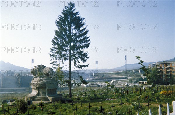 A cemetary in sarajevo, bosnia with the olympic stadium in the background, 1995.