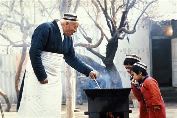 A grandfather with his grandsons, cooking rice pilaf, uzbekistan, 1990s.