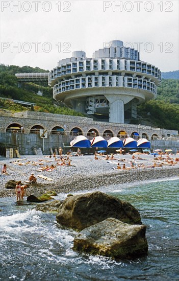 People sunning themselves on a pebble beach at a resort and health spa on the black sea in the crimea, ukraine.