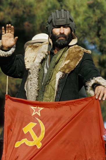 A pro-government fighter with a flag of the ex-soviet union (ussr) near kumsangir, tajikistan, january 1993.