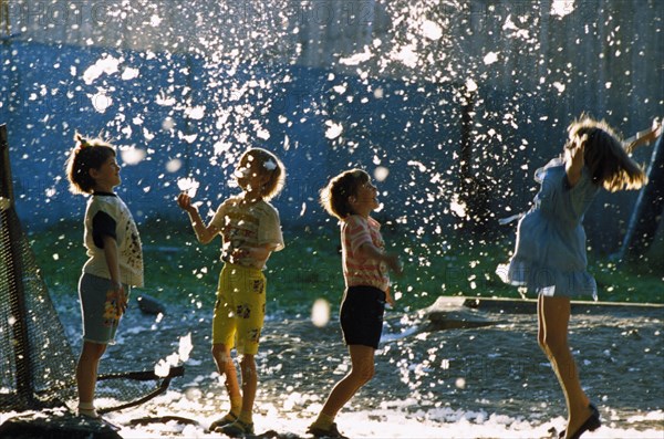 Children playing under a seeding poplar tree in petrozavodsk, russia, 1990s.