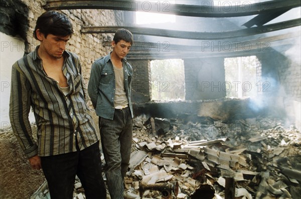 Two tajik men inside a house that was destroyed during fighting at the budenny state farm in kurgan-tyube, tajikistan, september 1992.