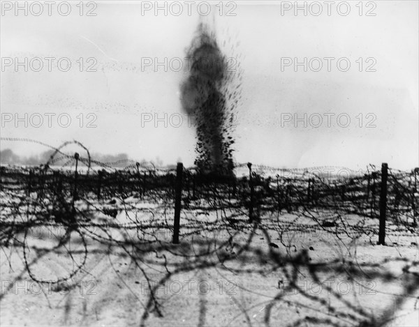 Shell bursting amongst the barbed wire entanglements.