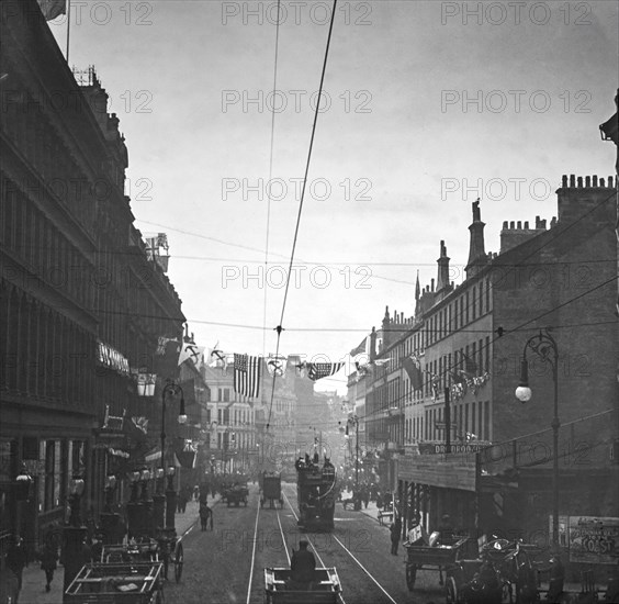 A black and white historic image of a street scene with horses