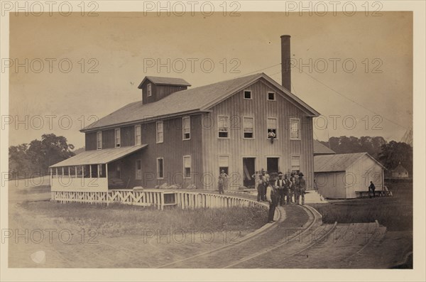 African American workers standing on railroad tracks in front of a storage facility, possibly at Giesboro cavalry depot