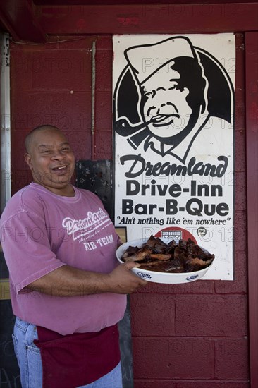 Proprietor of Dreamland BBQ holds food