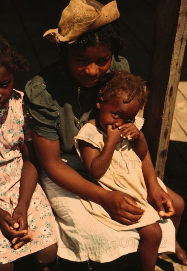 Three Negro children sitting on the porch of a house