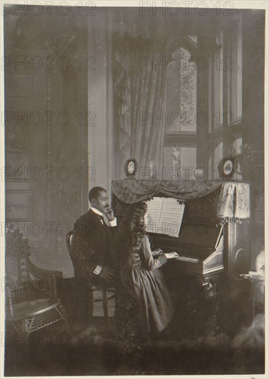 African American man giving piano lesson to young African American woman