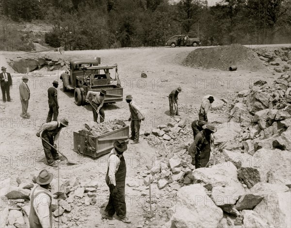 Prisoners breaking up rocks at a prison camp or road construction site