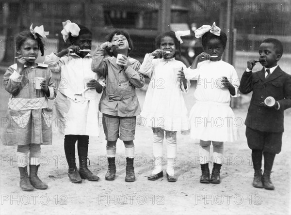 Six children brushing their teeth outside of school,