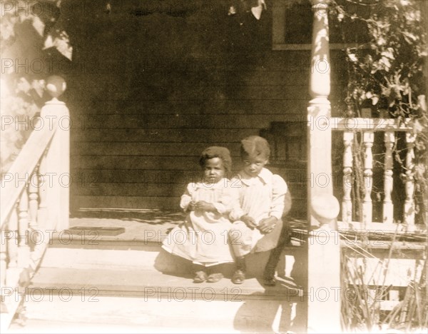 Two African American children sitting on steps to porch