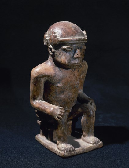 Coquero'. Man sitting with hands on knees and chewing coca leaves.