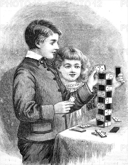 Children build a tower with dominoes / Kinder bauen mit Dominosteinen einen Turm