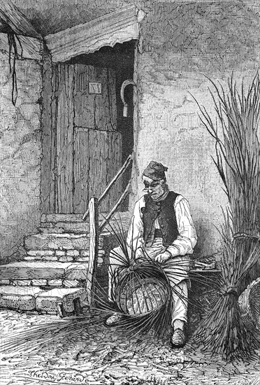 Wicker sits in front of his house and wilts a wicker basket  /  Korbflechter sitzt vor seinem Haus und flechtet einen Weidenkorb