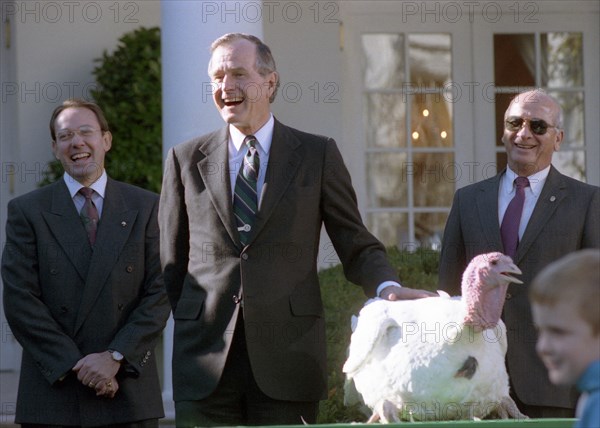 President Bush participates in the presentation and pardoning of the National Thanksgiving Turkey in the Rose Garden of the White House.  His grandson, Sam Leblond, pets the turkey during the ceremony. 14 November 1990 .