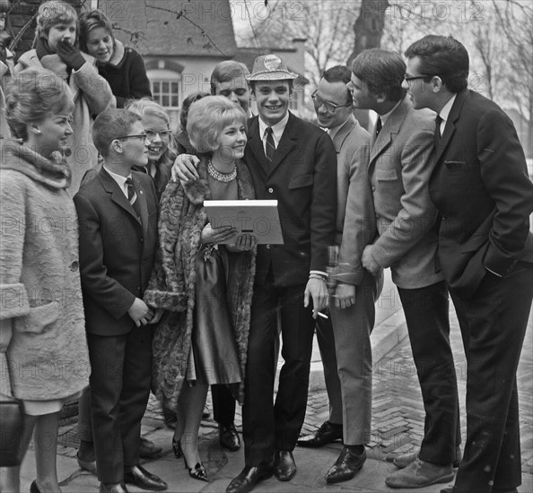 Willeke Alberti received first gold record from Phonogram director Jack Haslinghuis, Willeke outside with Rob de Nijs showing her trophy / Date 2 March 1964.