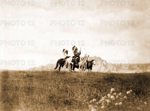 Edward S. Curits Native American Indians - Three Sioux Indians of horseback on plains with rock formation in background circa 1905.