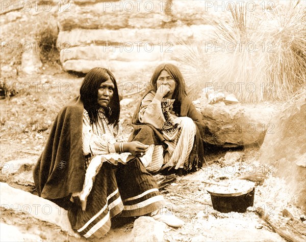 Edward S. Curits Native American Indians - Two Apache Indian women at campfire, cooking pot in front of one circa 1903.