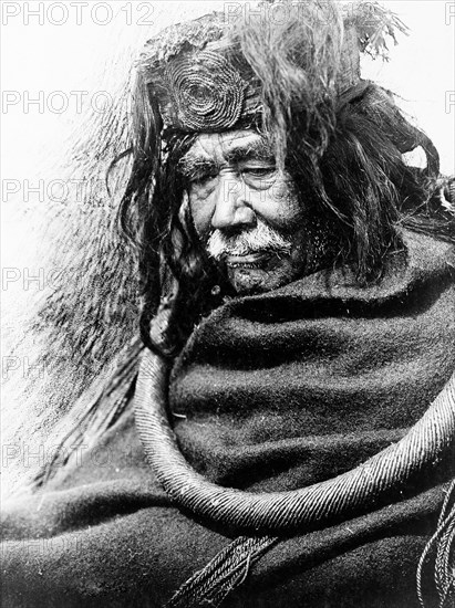 Edward S. Curits Native American Indians - Half-length portrait of Nakoaktok man, facing left, wearing cedar root ceremonial loop circa 1910.