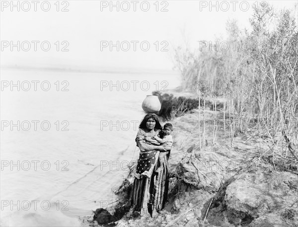 Edward S. Curits Native American Indians - Mohave Indian woman carrying water on her head and holding child circa 1903.