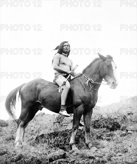 Edward S. Curits Native American Indians - Nez Percé man, wearing loin cloth and moccasins, on horseback circa 1910.