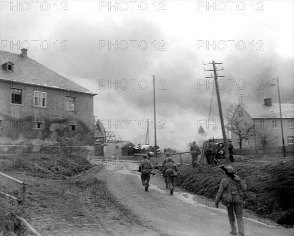 Infantrymen of the 90th Division, 3rd US Army, fight their way through Gottsmanngrun, Germany, being held by a company of Germans who are holding on to prevent the Americans from crossing the Saale River circa 4/1945.