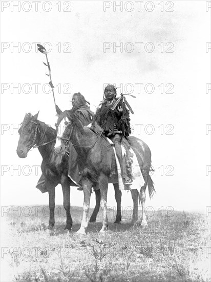 Edward S. Curtis Native American Indians - Two Atsina chiefs on horseback, one with feathered staff and one with a coup stick circa 1908.